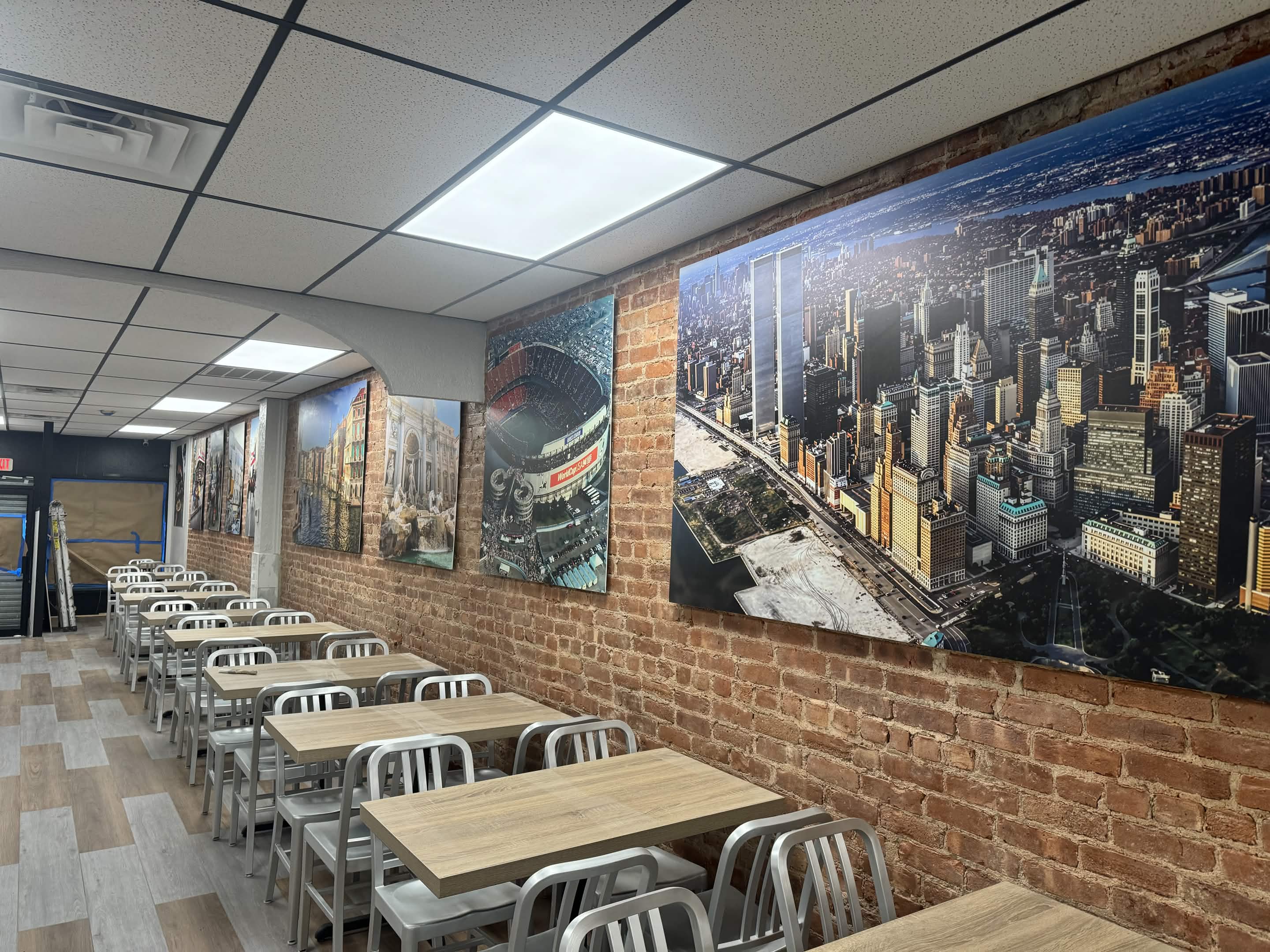 Restaurant interior with NYC skyline and stadium murals on brick wall